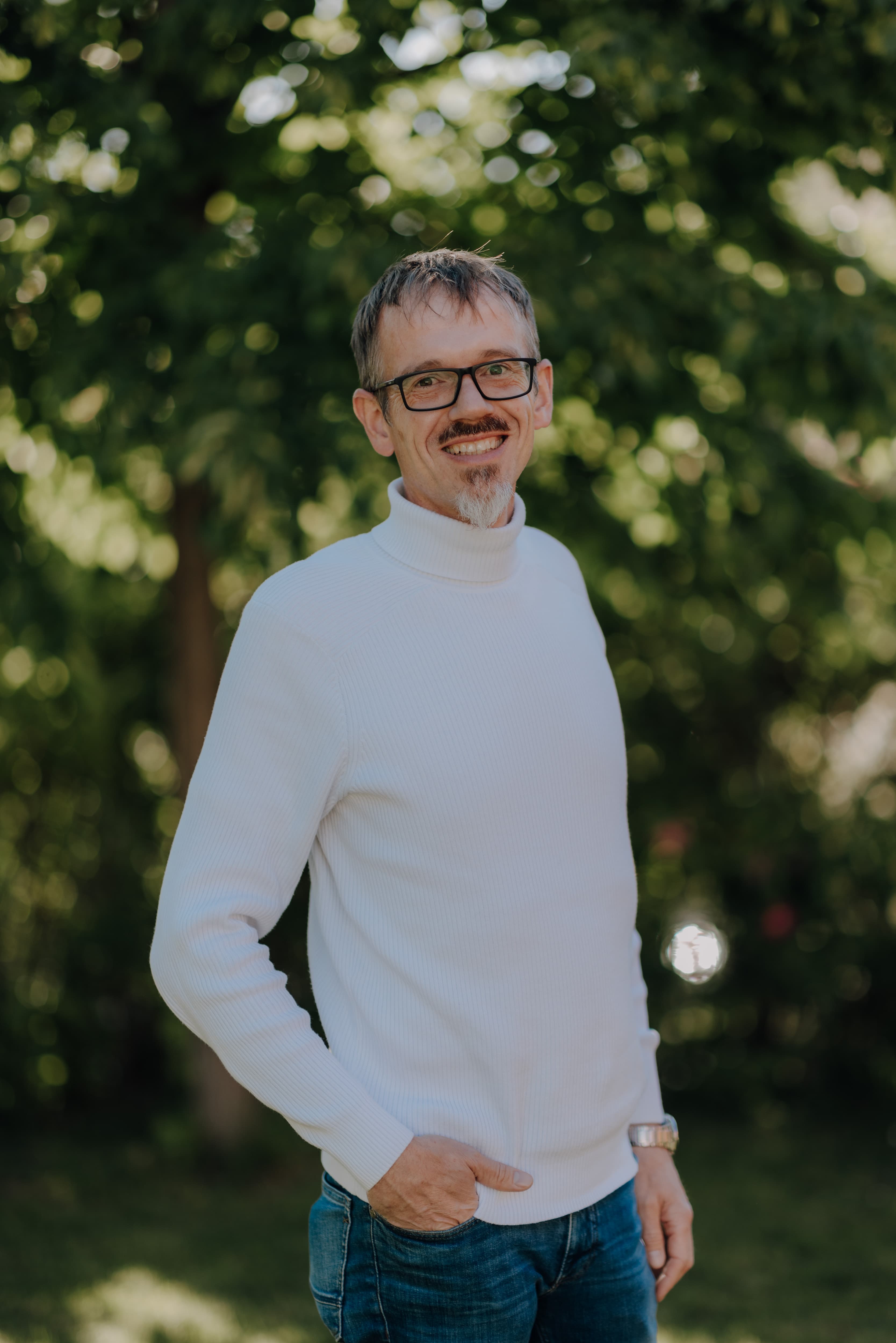 Pastor Lars Kortkamp from GEC Heilbronn preaches on stage with a Bible in his hand and a smile on his face.